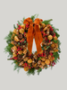 Decorative wreath with pine cones, berries, and a large orange bow on a light gray background